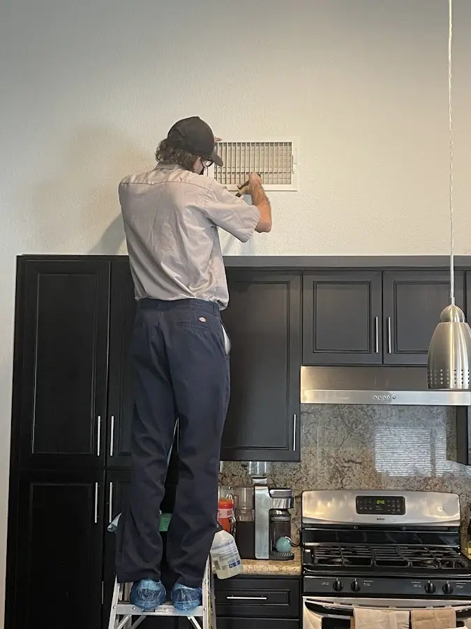 Technician inspecting an air vent during HVAC service in Patterson